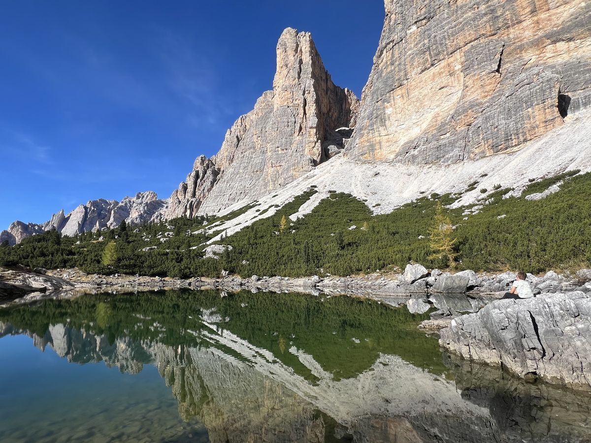 Lago alpino che riflette le pareti delle Dolomiti